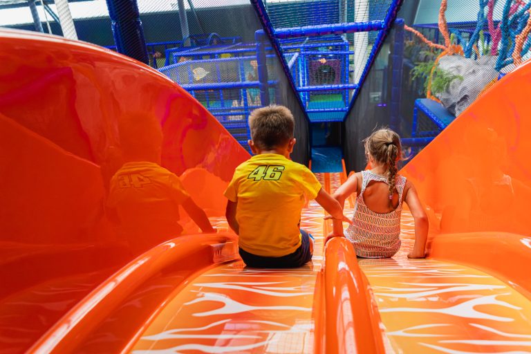 Zwei Kinder sitzen auf orangener Rutsche im Playworld Wien