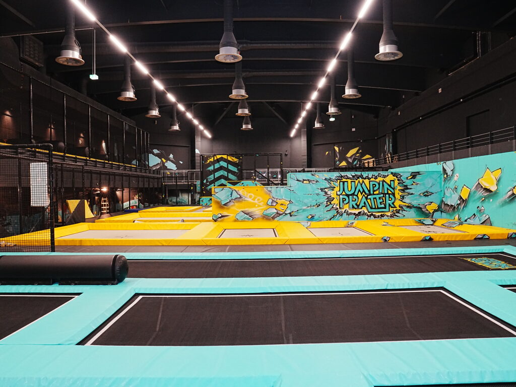 Trampolinsprungbereich im Indoor-Spielplatz mit gelben und blauen Trampolinen.