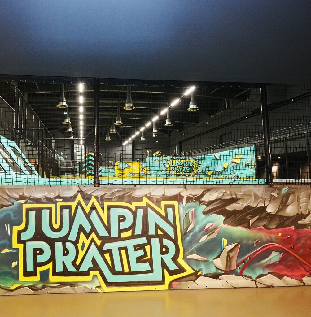 Farbige Wand mit Aufschrift Jumpin Prater in einem Indoor-Spielplatz.